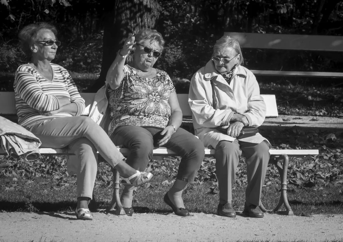 Three older women sitting together on a bench